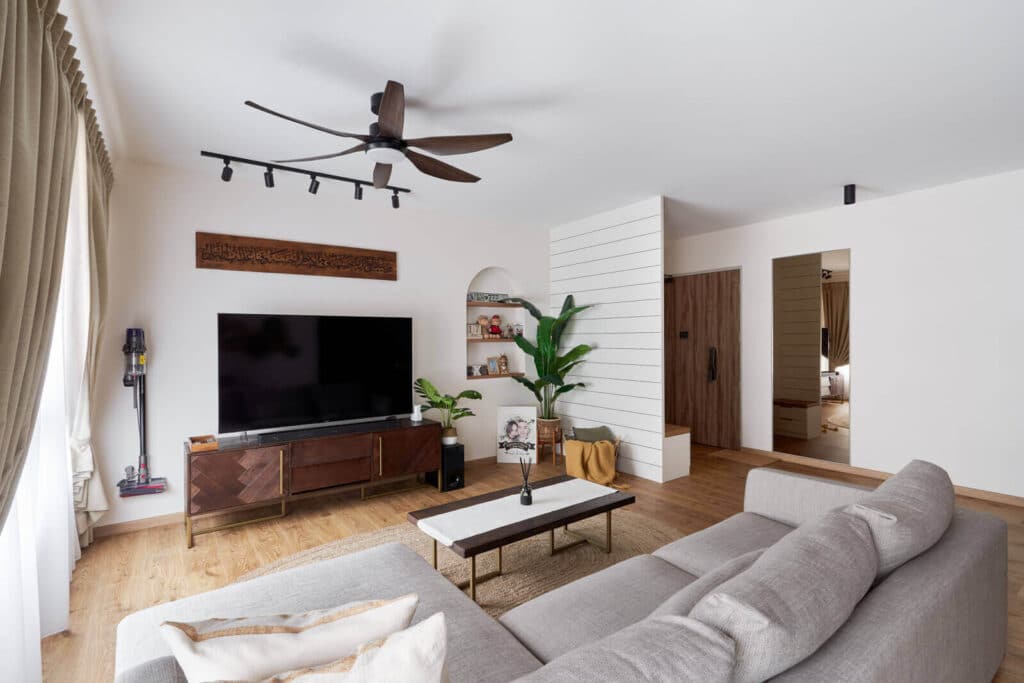 Chic bungalow design living room with grey sectional sofa, warm wood flooring, niche shelving and indoor plants