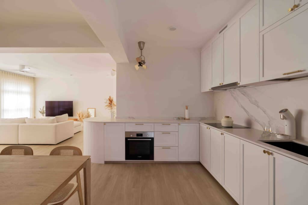 Bright bungalow design kitchen with white shaker cabinets, marble backsplash and open-plan flow to dining area