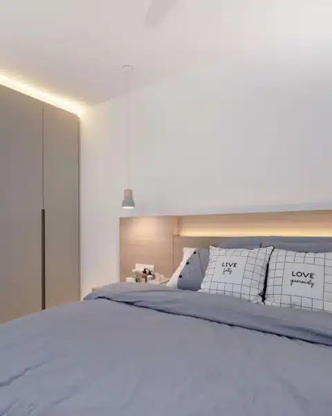 Minimalist room with built-in wardrobe, warm headboard lighting and a slim pendant beside the bed
