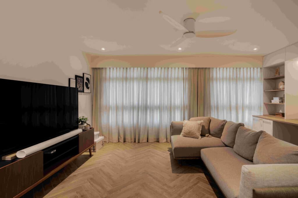 Modern bungalow design living room featuring herringbone wood floor, neutral sectional and full-height drapery