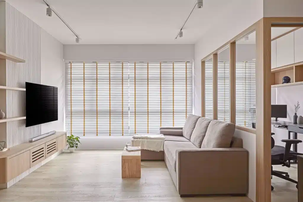 Light-filled minimalist condo living room with neutral sofa, TV wall and full-height blinds designed by Lemonfridge Studio.
