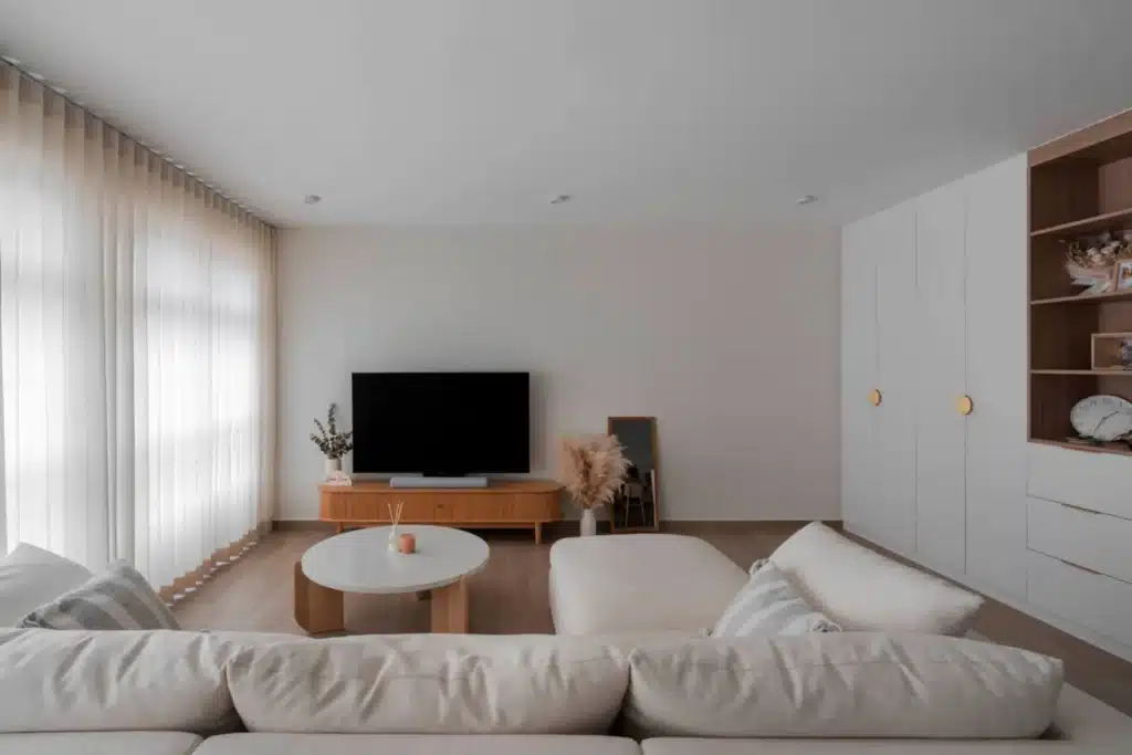 Warm wood Scandinavian-inspired living room with off-white sofa, round coffee table and built-in cabinets by Lemonfridge Studio.